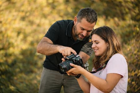 Instructor guiando a una alumna mientras revisan la cámara durante un curso de fotografía en Málaga, aprendiendo fotografía paso a paso con luz natural.
