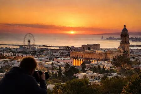 Fotógrafo capturando el atardecer de Málaga desde un mirador, ejemplo de aprendizaje práctico en cursos de fotografía en Málaga con luz natural y paisaje urbano.